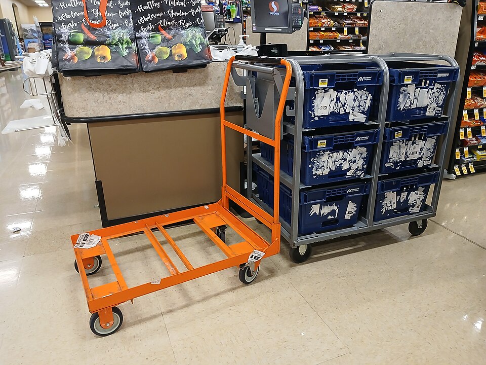 Carrinho de mão laranja transportando caixas azuis